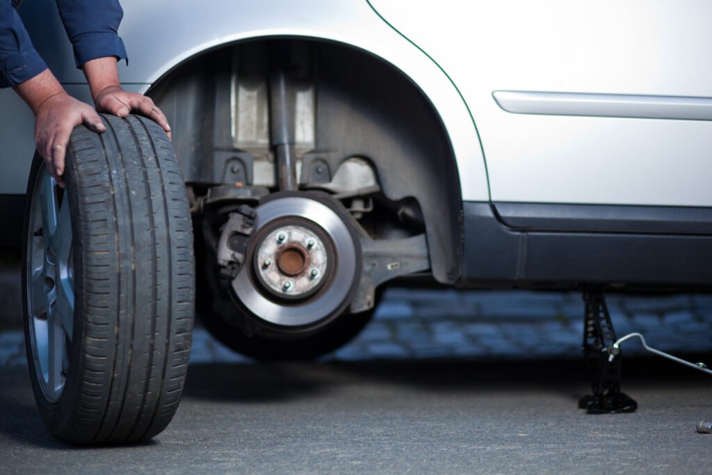 Mechanic changing a wheel of a modern car (shallow DOF; color toned image) Tire Rotation and Wheel Alignment